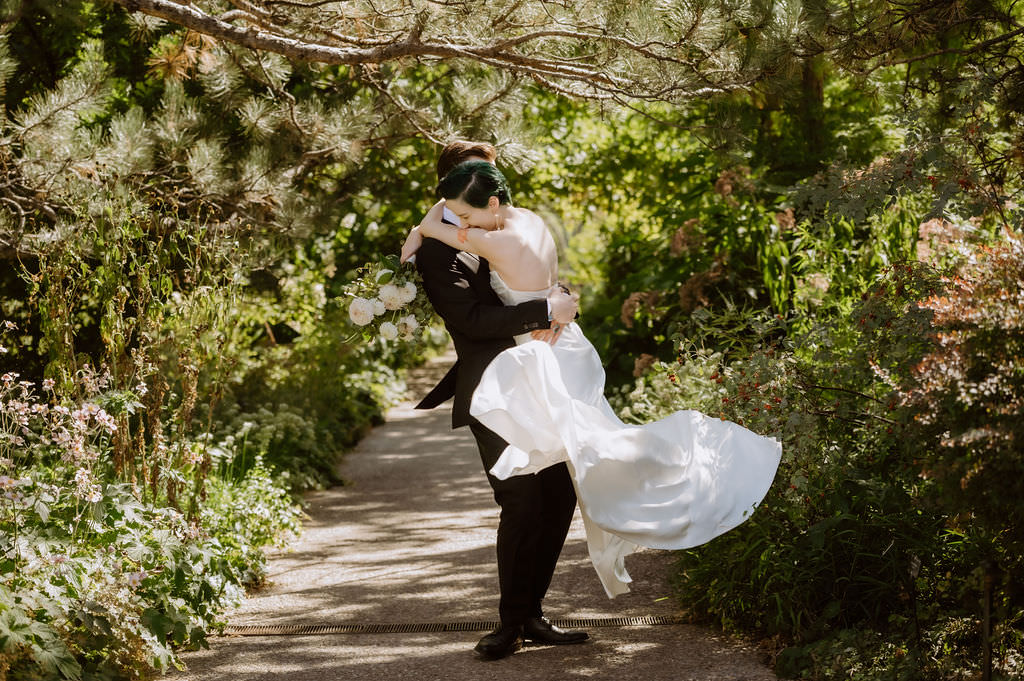 A person holding up their partner as they spin on a walking path 