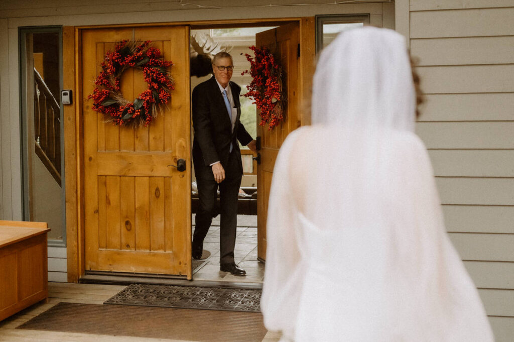 A father walking out of a door for a first look with their daughter on her wedding day 