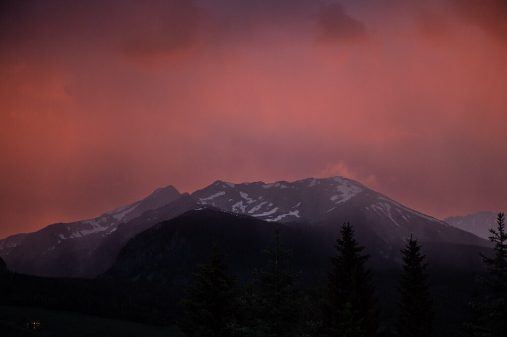 A mountain with patches of snow during a firey sunset 