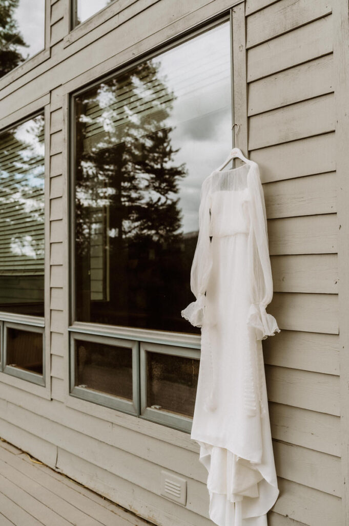 A wedding dress hanging on the side of a house 
