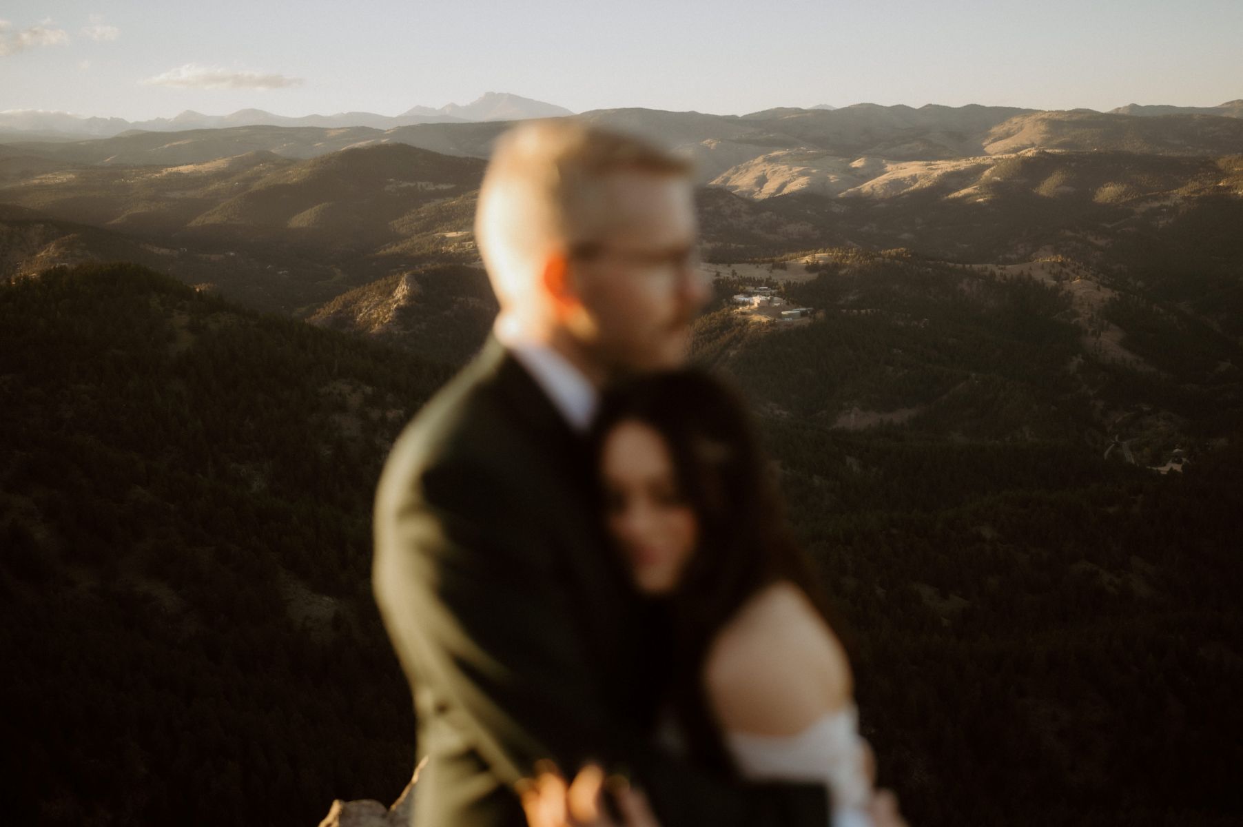 a blurry image of a couple embracing next to the mountains 
