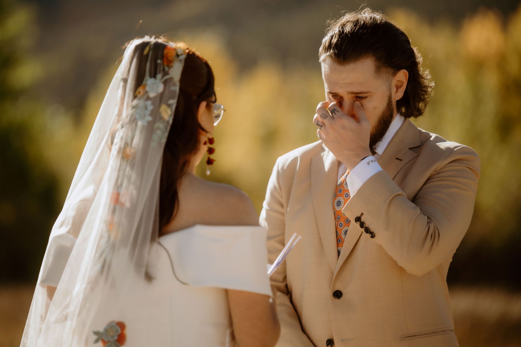 a couple having their wedding ceremony at twin lakes in colorado the woman is reading vows to her partner who is teary eyed